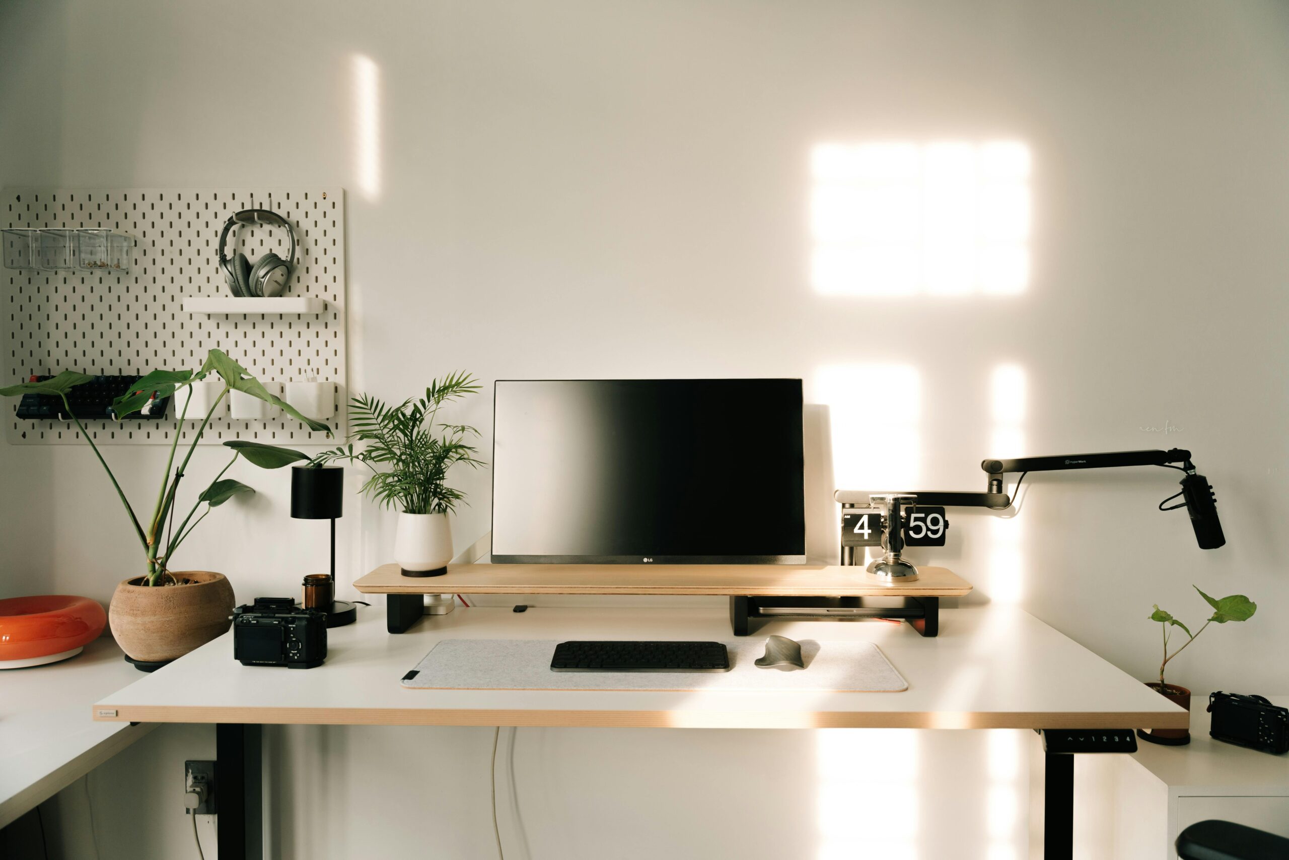A clean, minimalist desk setup with monitor and plants.