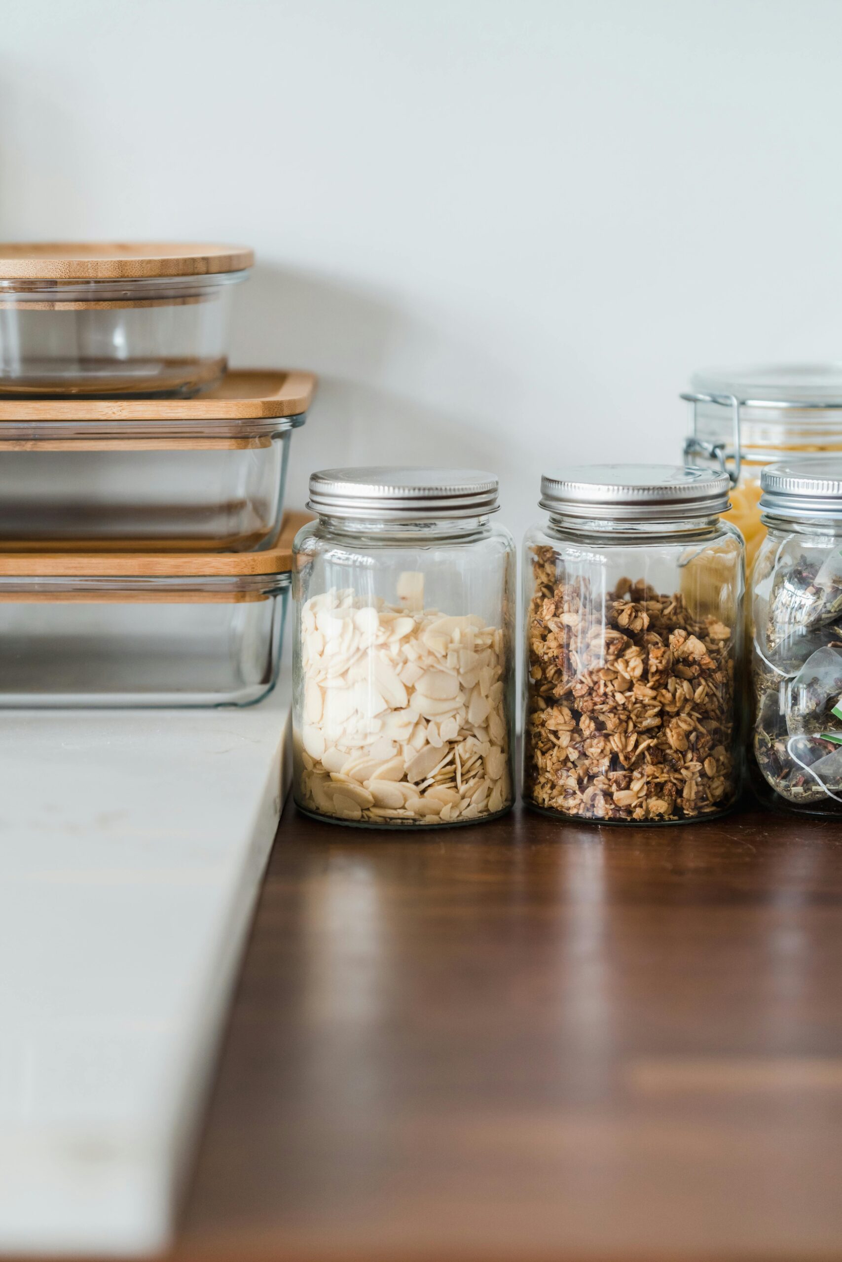 A neat kitchen counter setup with glass jars, organized food storage containers, and warm wood surfaces.