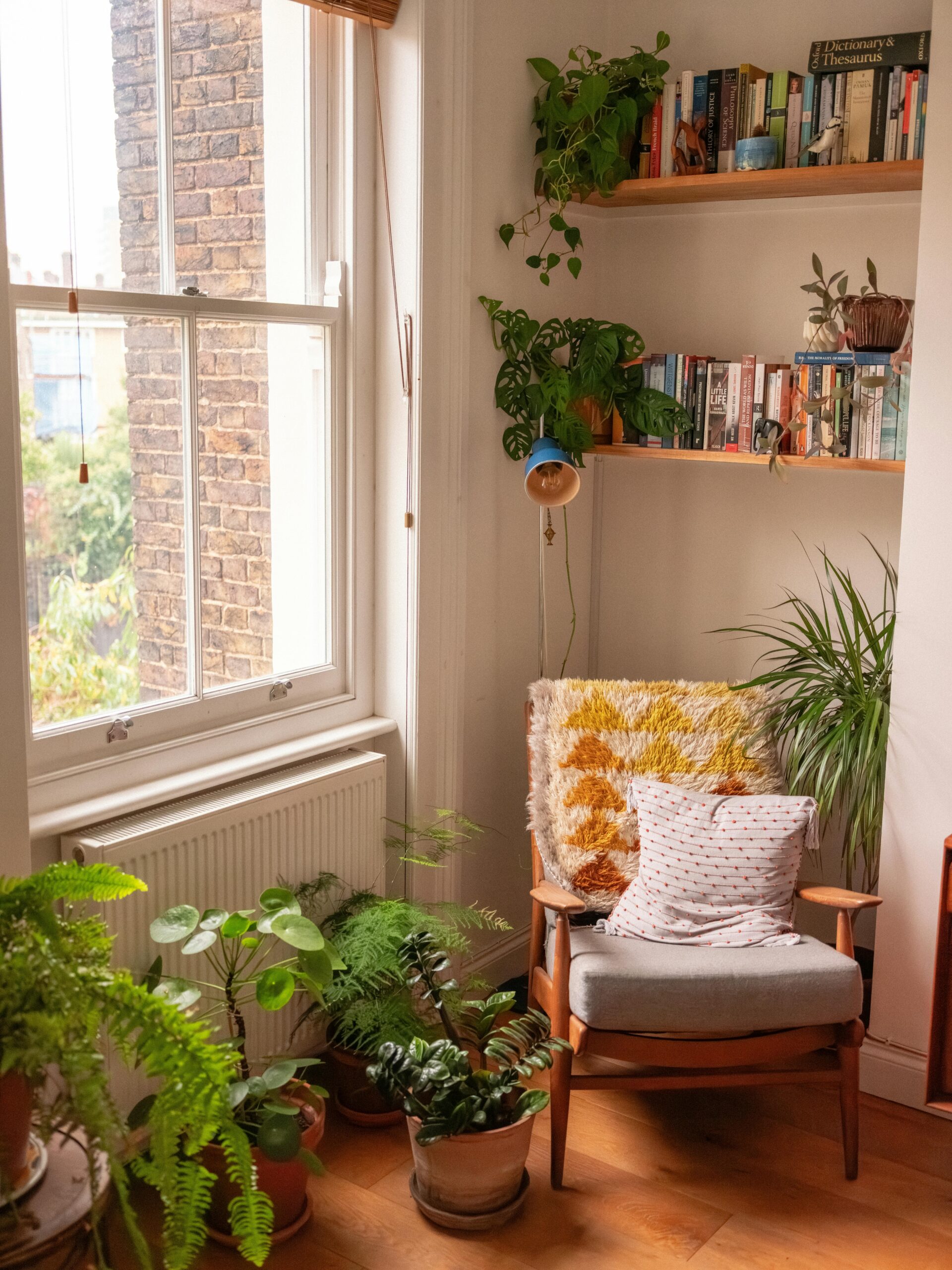 A bright, cozy reading nook corner featuring a comfortable armchair, indoor plants, and a bookshelf — perfect for relaxation.