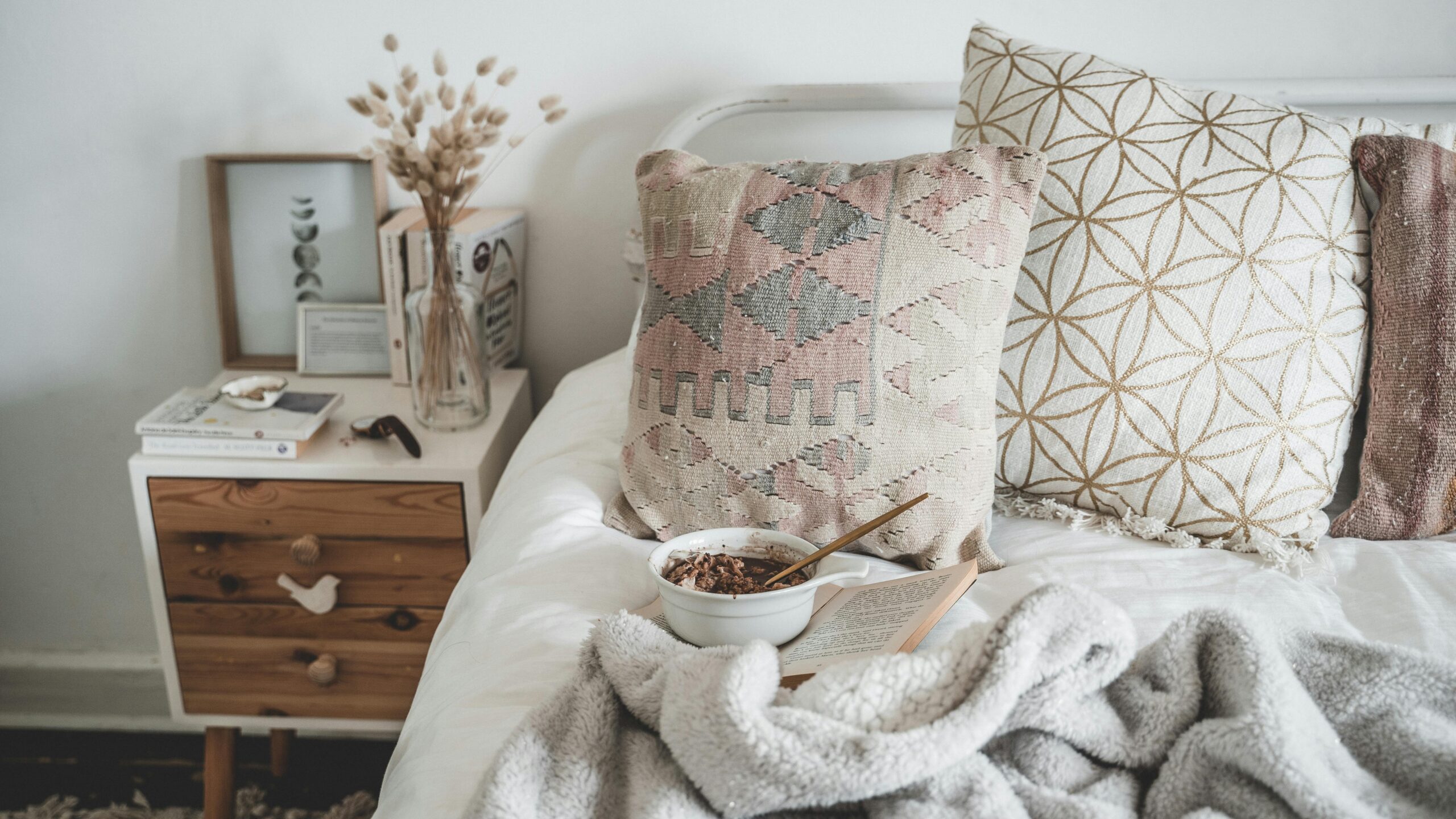 A warm, inviting bedroom corner with soft pillows, cozy blankets, and a calm morning setup.